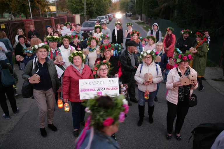 Grupa ludzi na ulicy w kwiatowych wiankach na głowie