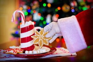 Zdjęcie przedstawia rękę świętego Mikołaja, która trzyma ciastko w kształcie gwiazdki