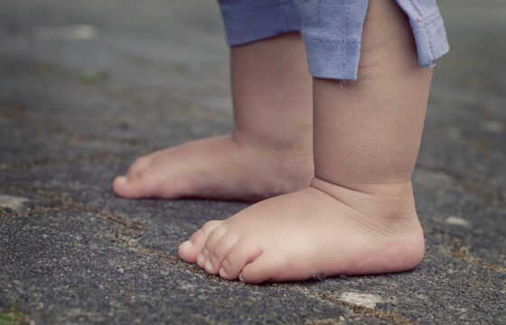 Bose stopy małego dziecka, w spodenkach za kolana