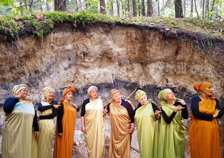 Osiem kobiet w starszym wieku pozuje do zdjęcia, ubrane są w jednym stylu, na głowach mają turbany.