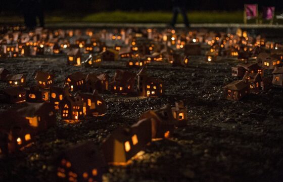 Zdjęcie: ustawione na ziemi małe gliniane domki, ze świeczkami wewnątrz.