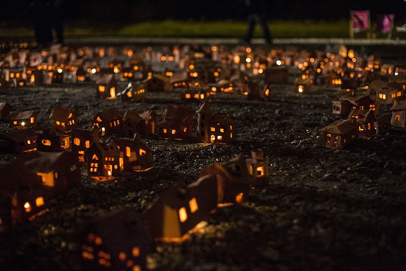 Zdjęcie: ustawione na ziemi małe gliniane domki, ze świeczkami wewnątrz.