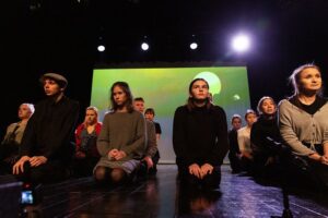 Zdjęcie - kilkunastoosobowa grupa młodzieży siedzi na scenie