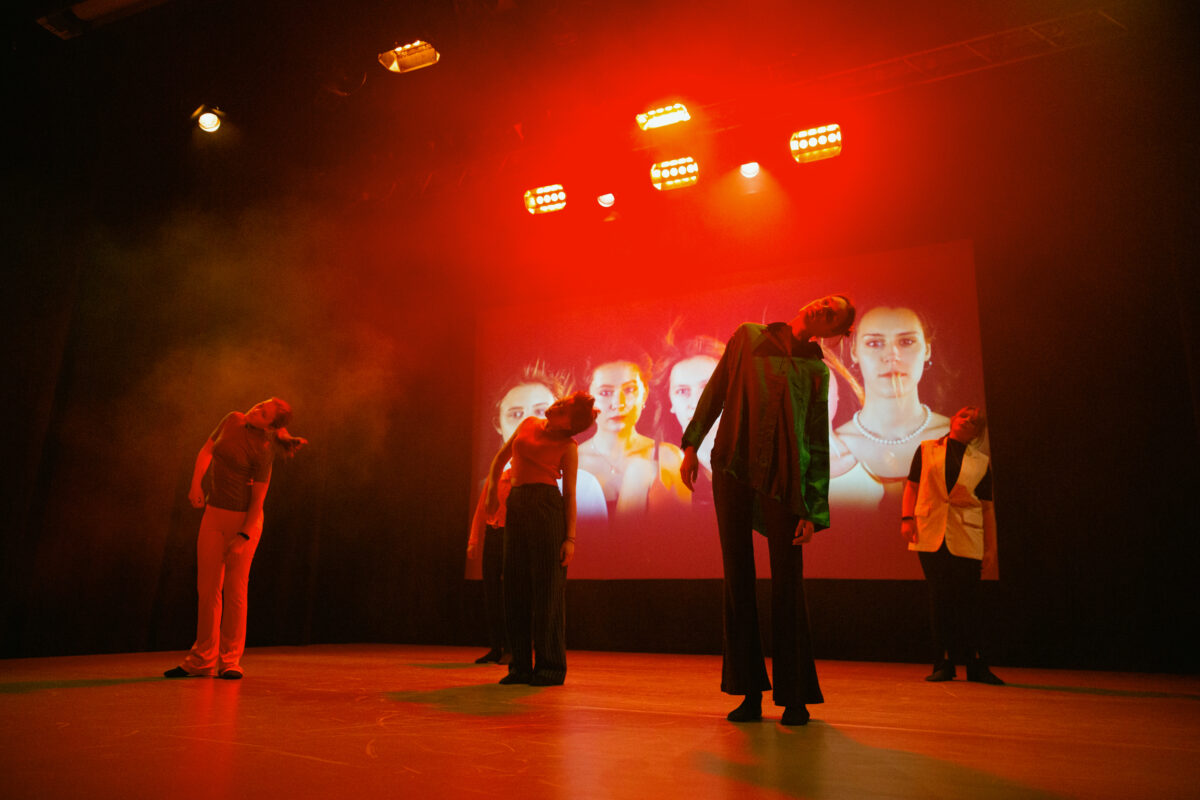 Cztery młode tancerki na scenie, za nimi na dużym ekranie fotografia ich twarzy
