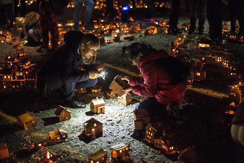 Miniaturowe gliniane domki. Jest ich bardzo dużo. Rozstawione są na ziemi na dużej przestrzeni, wewnątrz nich palą się malutkie świeczki. Pośród nich wędrują ludzie