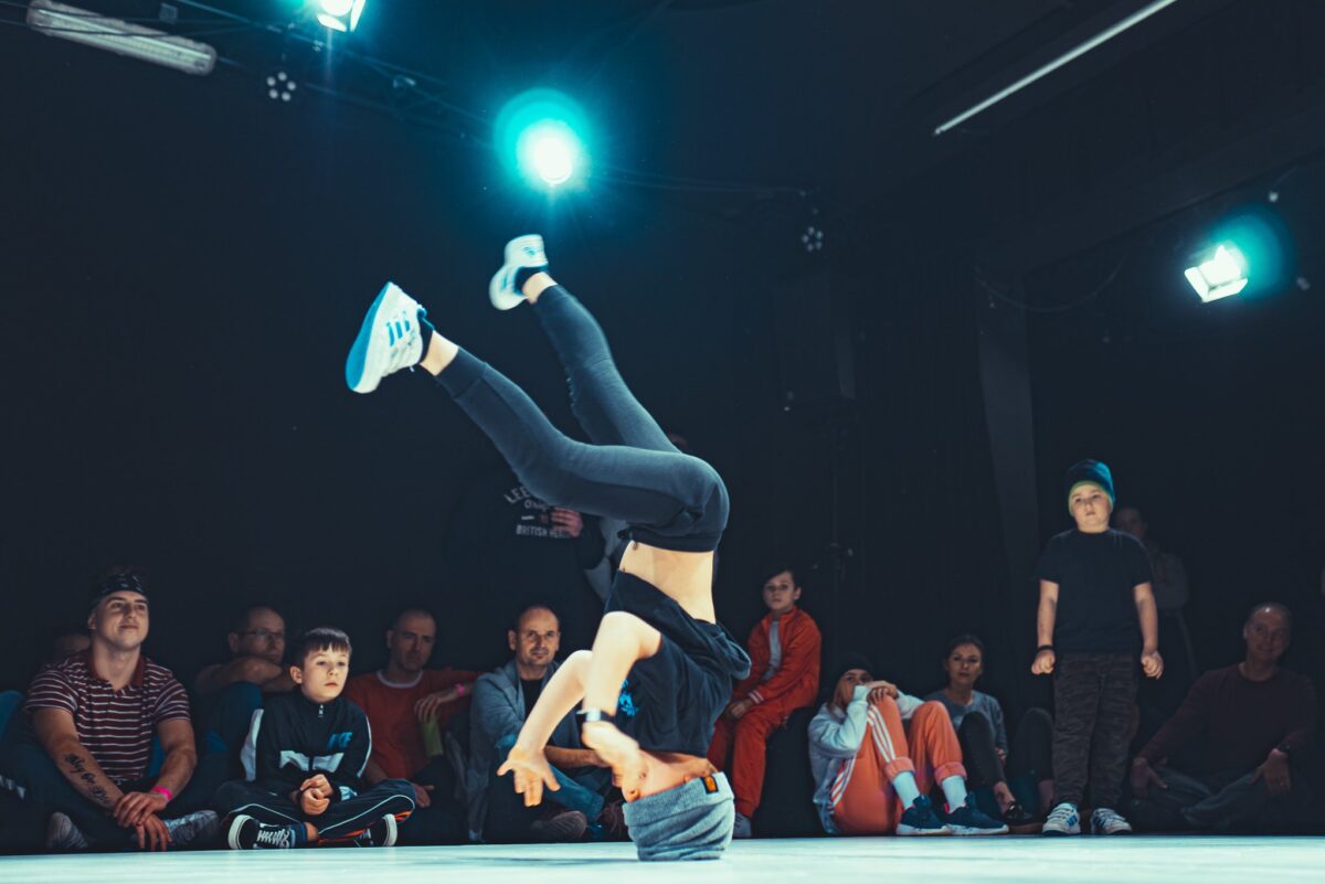 Chłopak na scenie - tańczy breakdance, na głowie. Za nim siedzą widzowie