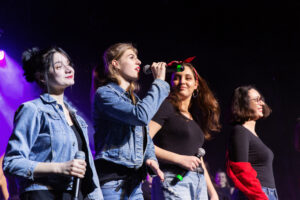 Grupa dziewczyn na scenie z mikrofonami w dłoniach