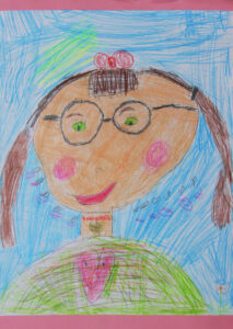 Portret mamy narysowany przez dziecko - kobieta w okularach, z kitkami