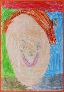 Portret mamy narysowany kredkami ołówkowymi przez dziecko, kobieta ma bardzo krótkie włosy, uśmiecha się