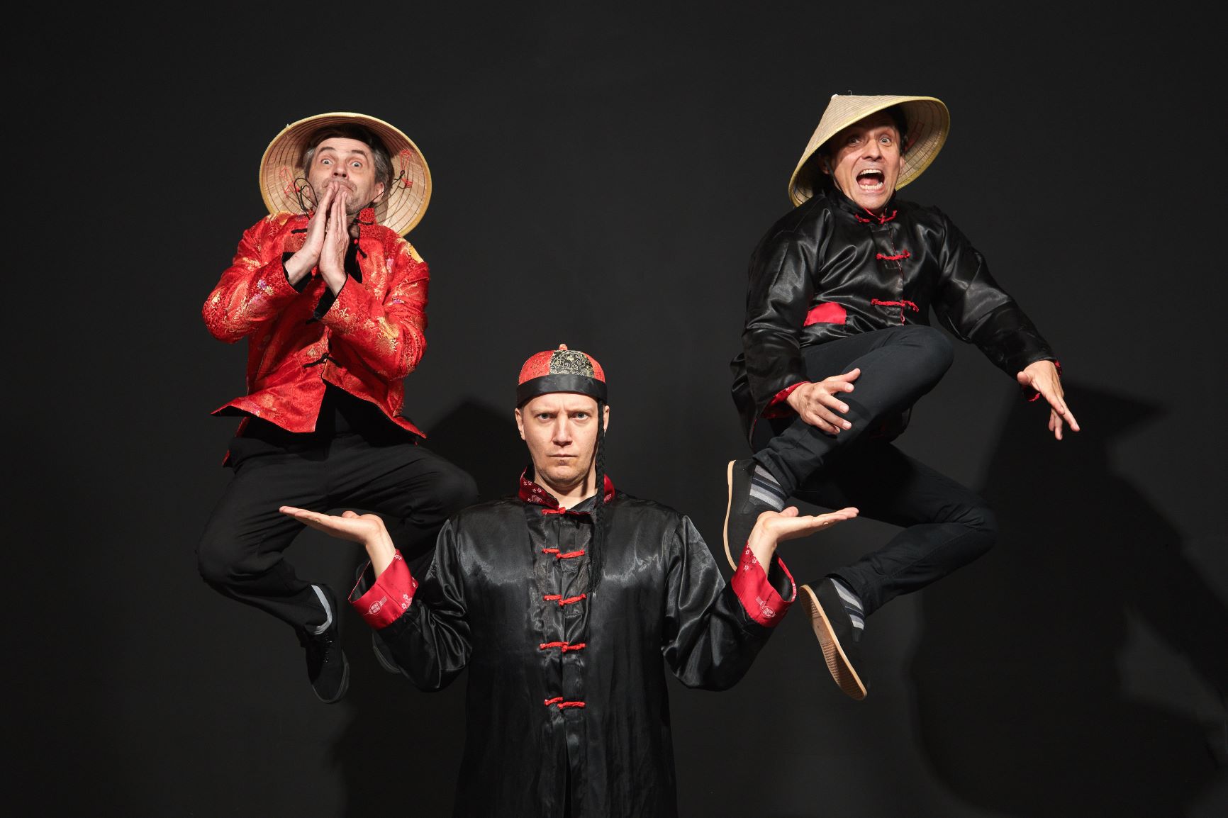 Trzech mężczyzn na scenie w kostiumach przywodzących na myśl stereotypowego Chińczyka.