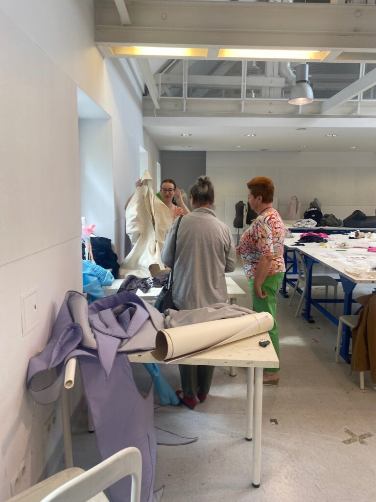 Kobiety w magazynie projektowania mody - na stołach leżą materiały