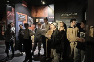 Zdjęcie przedstawia grupę 8 osób oglądających wystawę historyczną.