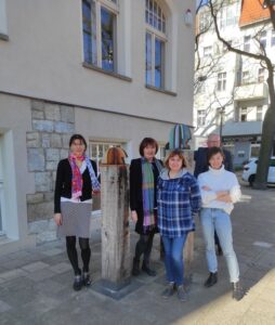 Grupa 5 osób stoi przed budynkiem frontem do kamery.