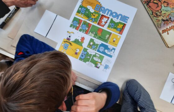 Zdjęcie z góry, głowa chłopca, przed nim komiks z napisem Bamonie