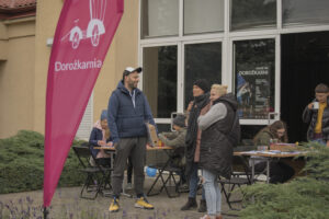 Kilka osób w jesiennej odzieży stoi przed budynkiem