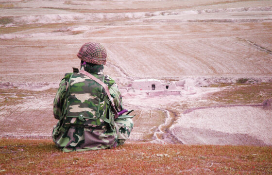 Żołnierz w umundurowaniu bojowym siedzi na poligonie