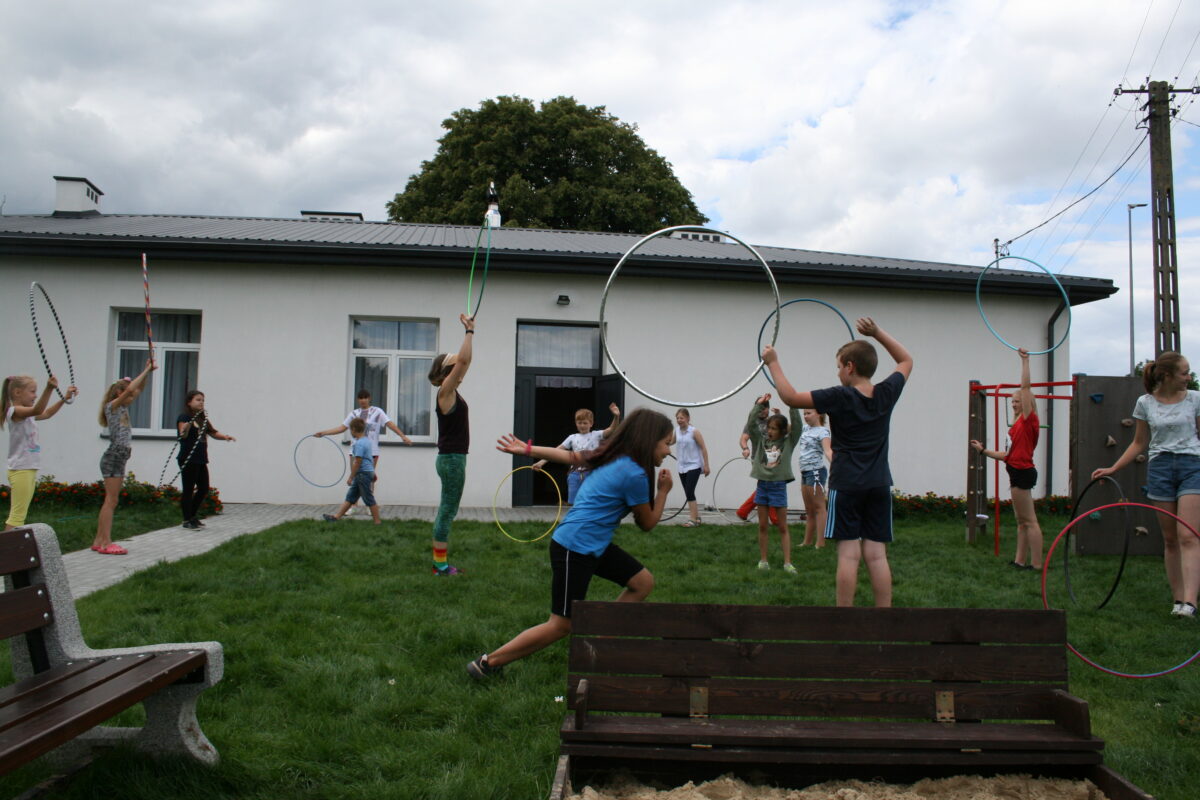 Dzieci ćwiczące z hula hop na powietrzu przed budynkiem