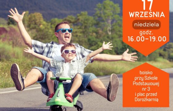 na drodze na dziecięcej hulajnodze siedzą kilkuletni chłopiec i młody mężczyzna. Obaj się uśmiechają, są w przeciwsłonecznych okularach