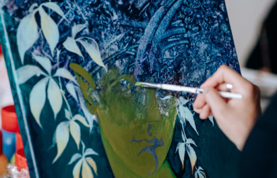 Osoba malująca obraz przedstawiający kobietę z włosami z liści bluszczu