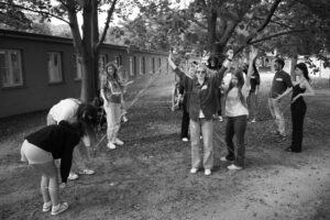 Grupa młodych ludzi na trawniku z drzewami, robi instalację ze sznurka