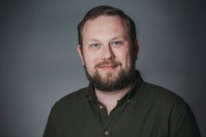 Młody uśmiechnięty mężczyzna z brodą ubrany w koszulę