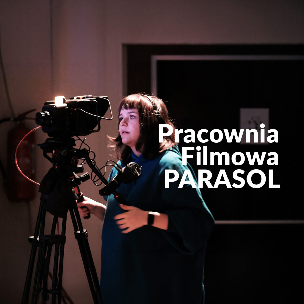 Zdjęcie kobiety wpatrzonej w kamerę. Rejestruje wydarzenie. Napis "Pracownia Filmowa PARASOL"